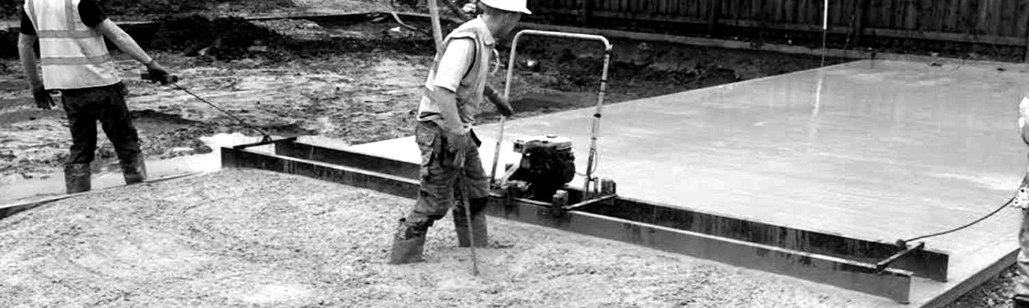 Two operatives levelling a fresh concrete slab with a vibrating screed