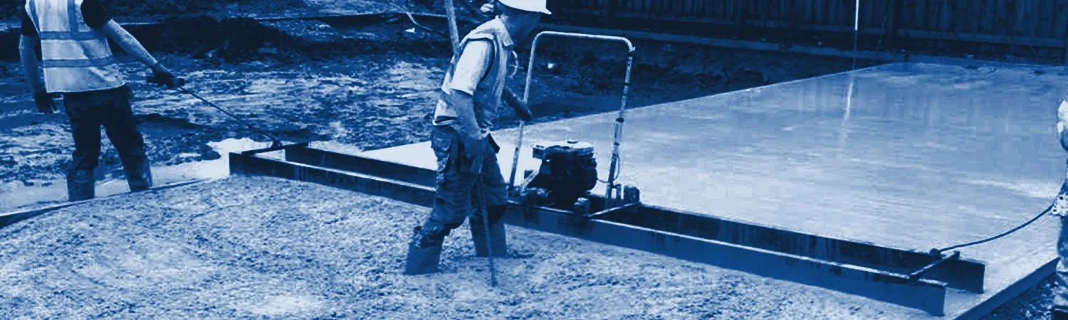 Two operatives levelling a fresh concrete slab with a vibrating screed