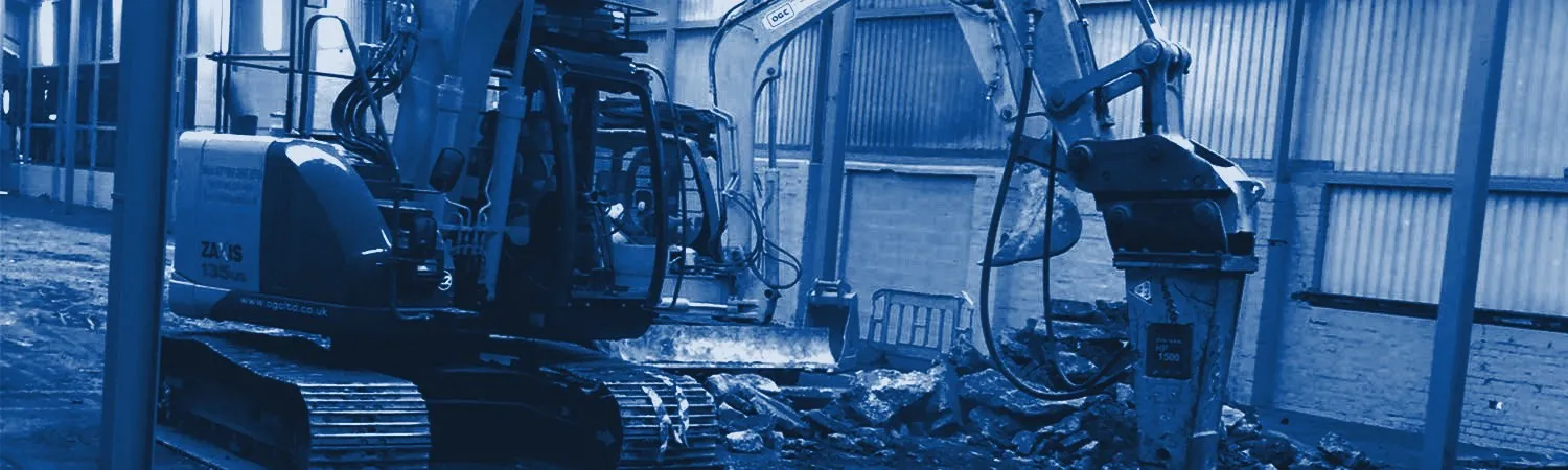 Excavators breaking out and loading inside an industrial building