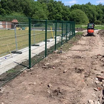 Long run of green mesh security fencing on a cleared site
