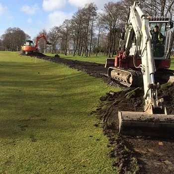 Two excavators cutting a new path route through open parkland