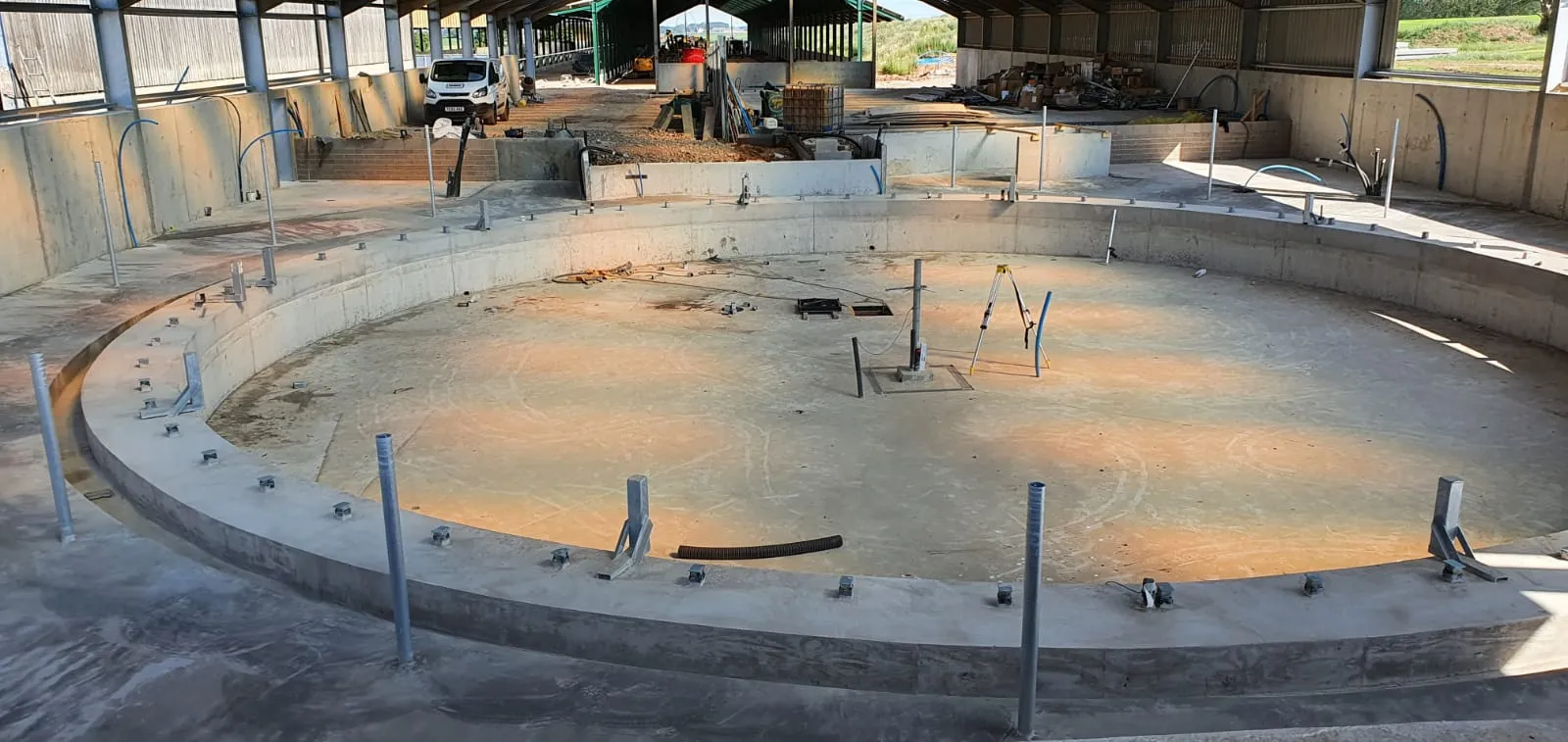Finished circular concrete base for a rotary milking parlour with fixing bolts set in