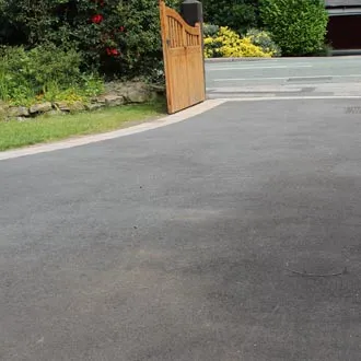 Tarmac driveway curving to a timber gate