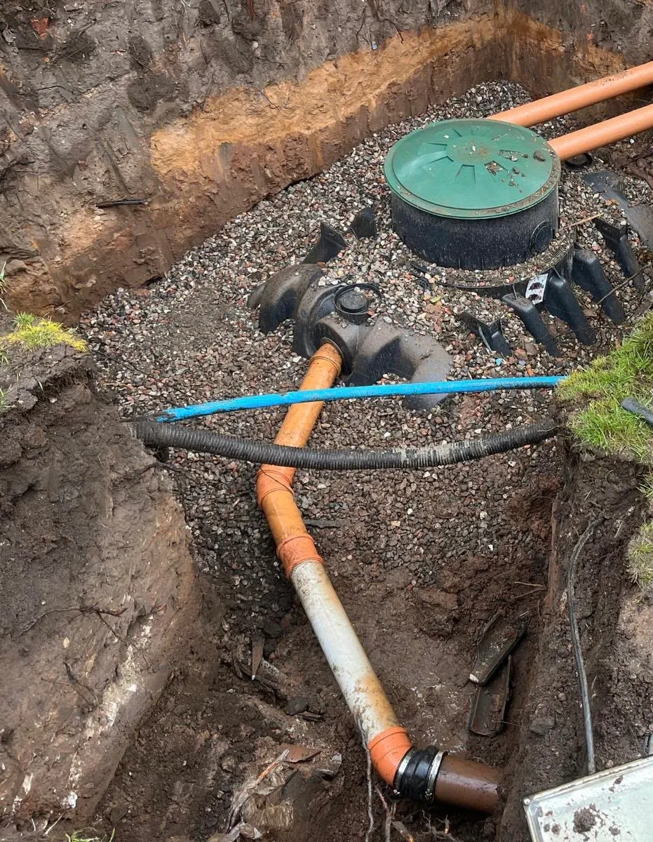 Treatment plant lid with inlet pipework and cable duct running through a trench